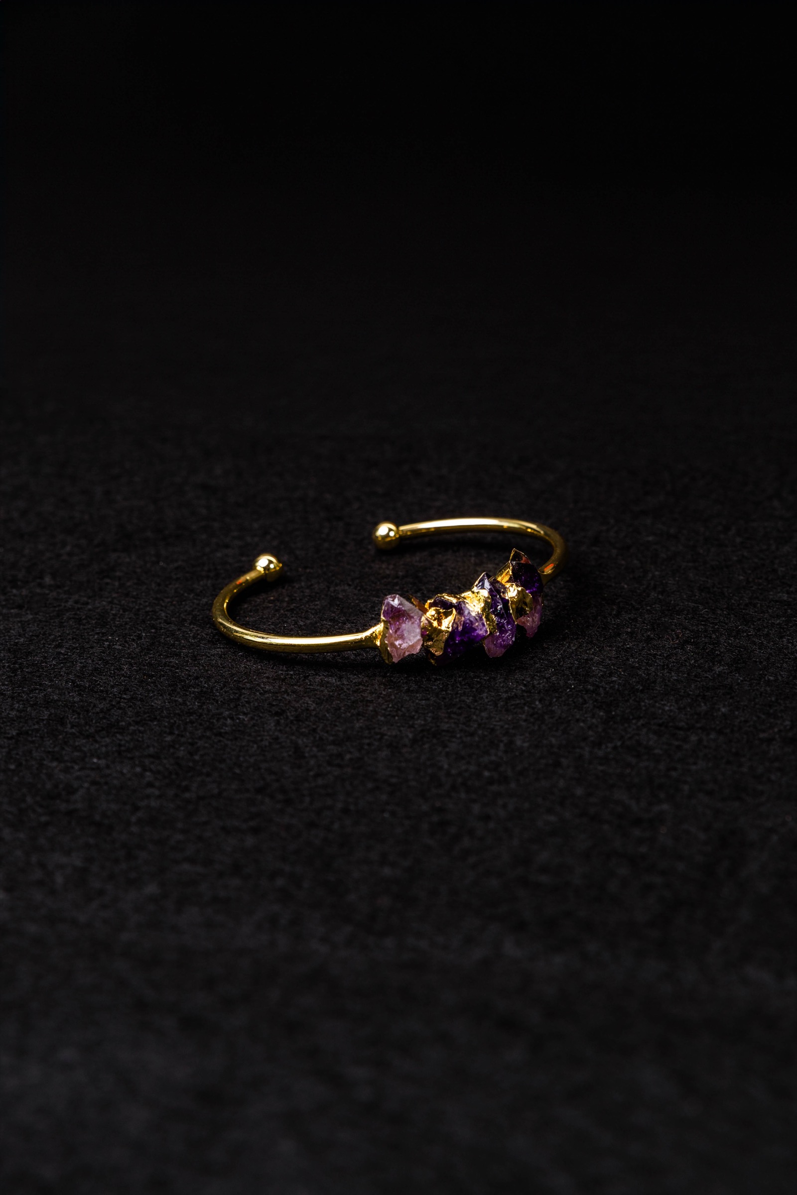 Fotografía de producto de una pulsera dorada con piedras de colores