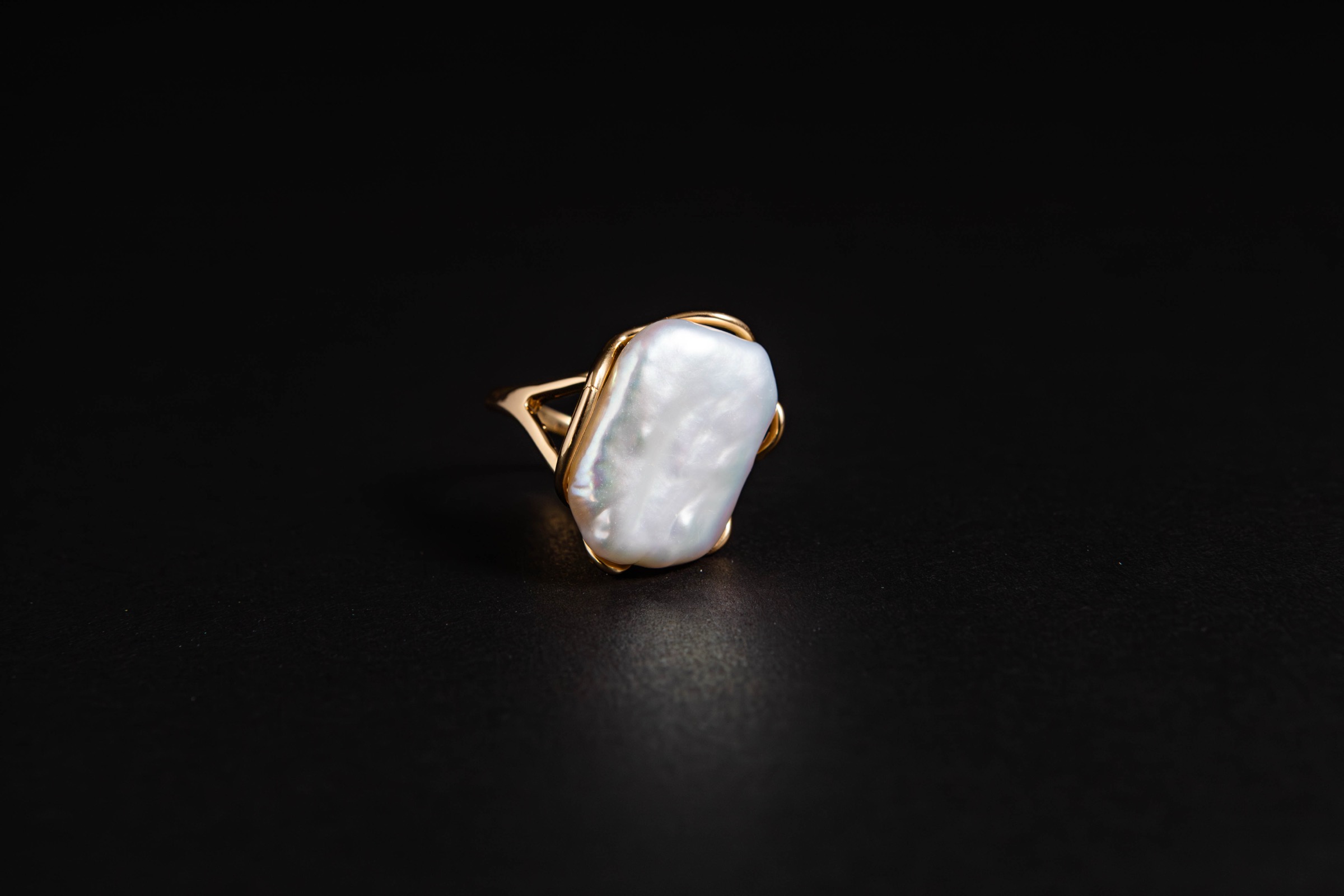 Fotografía de producto de un anillo con piedra nacarada sobre fondo negro