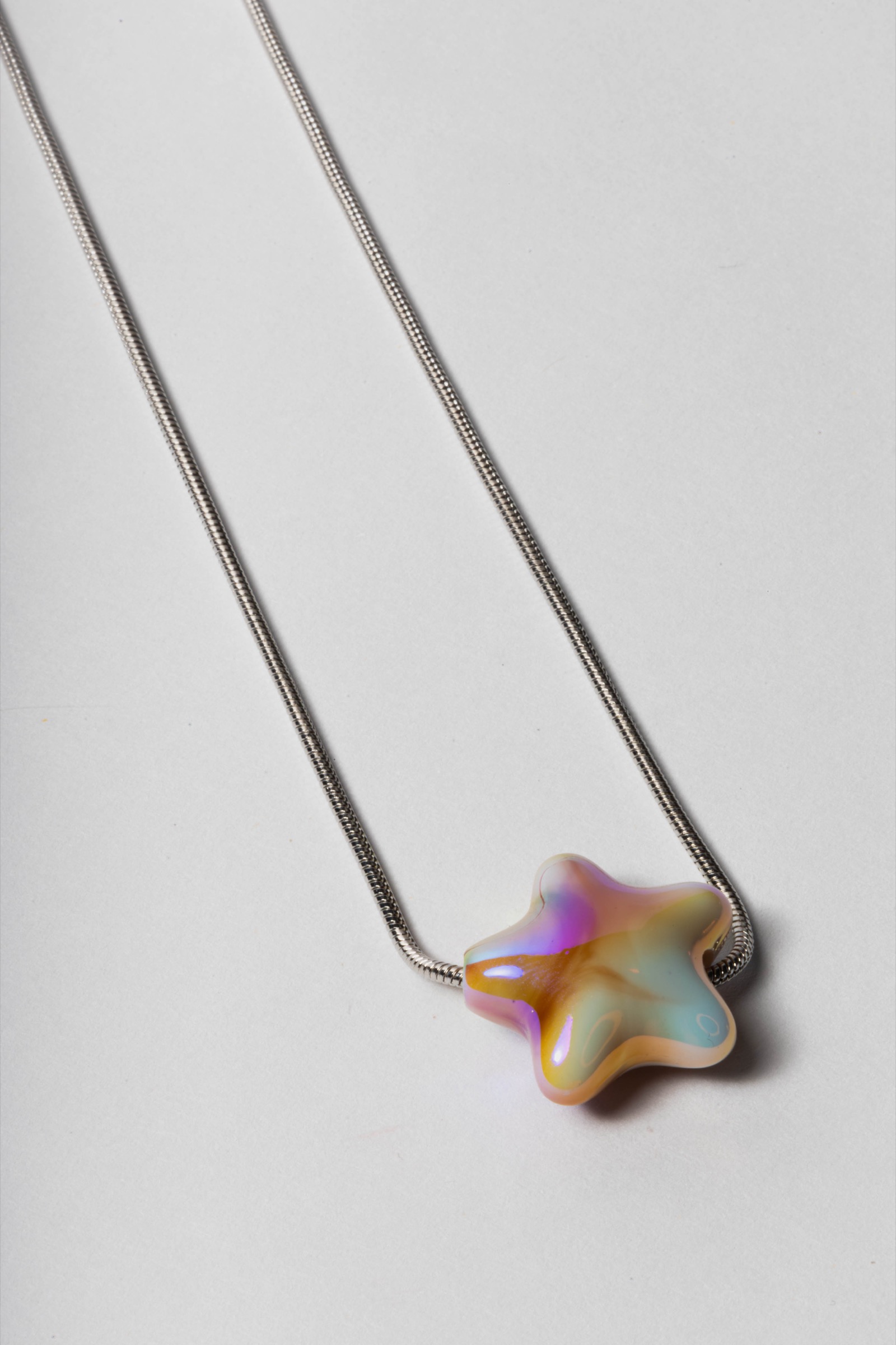 Fotografía de producto de un collar con dije de colores sobre fondo claro