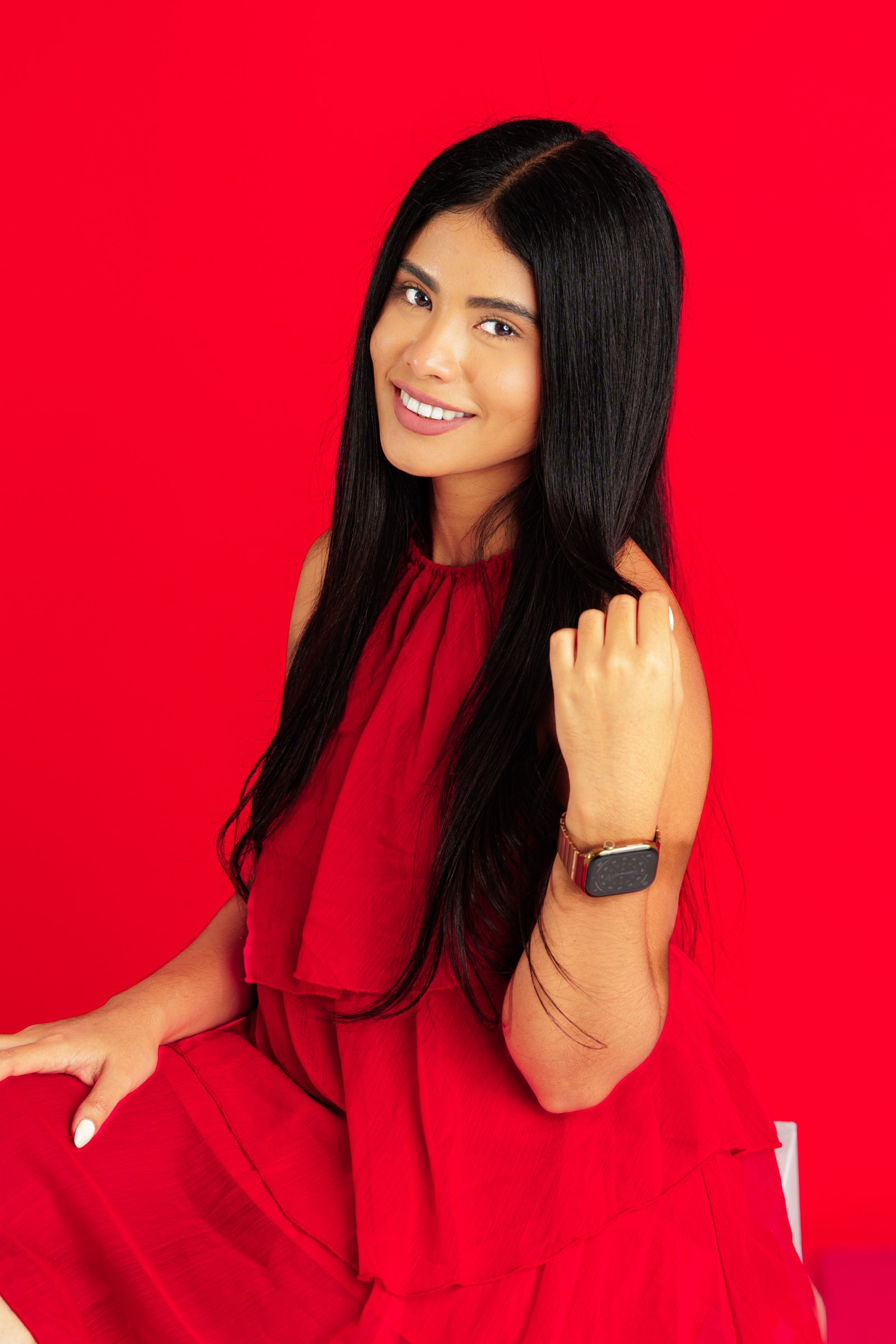 Retrato de una mujer con vestido rojo frente a un fondo rojo de estudio