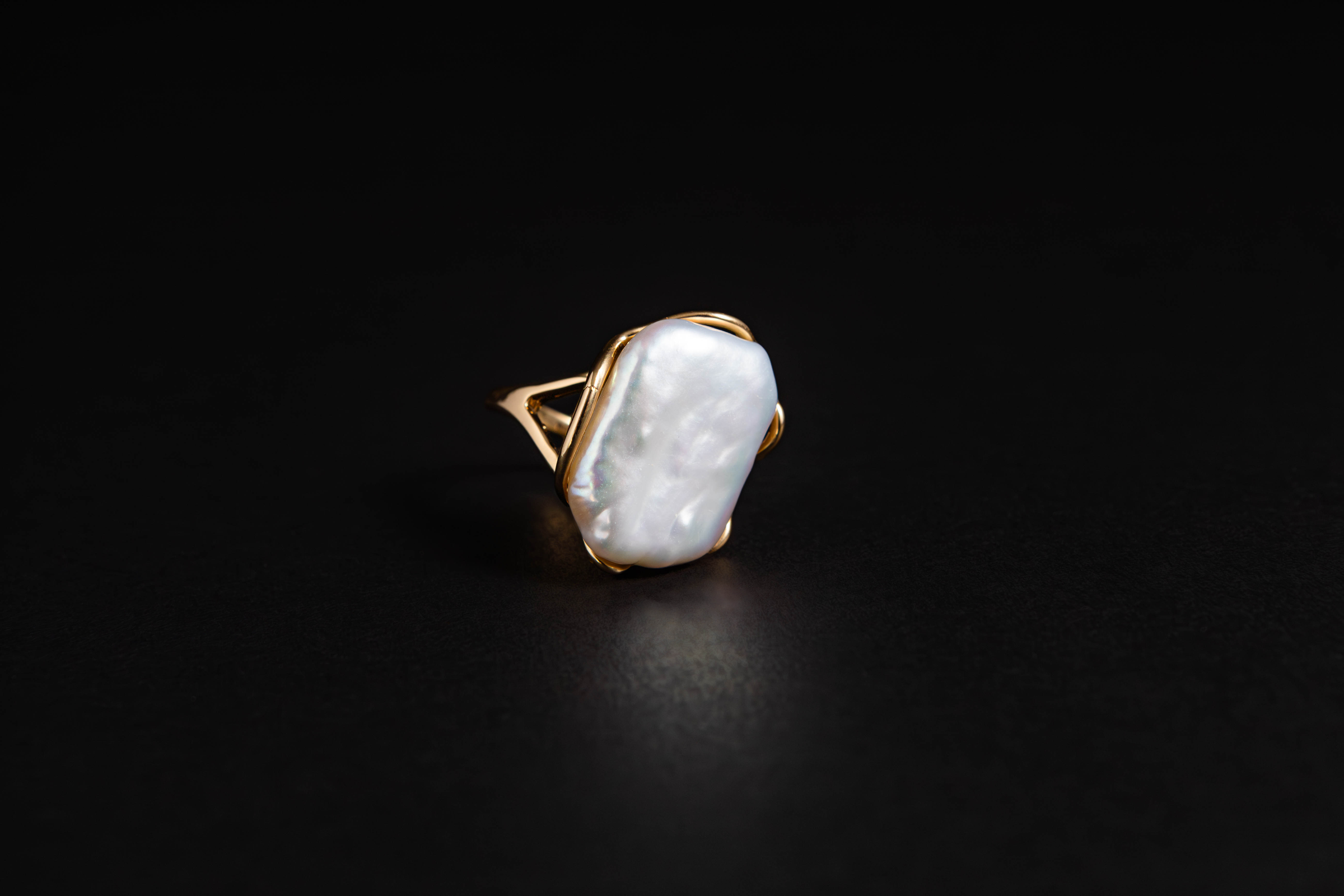Fotografía de producto de un anillo con piedra nacarada sobre fondo negro