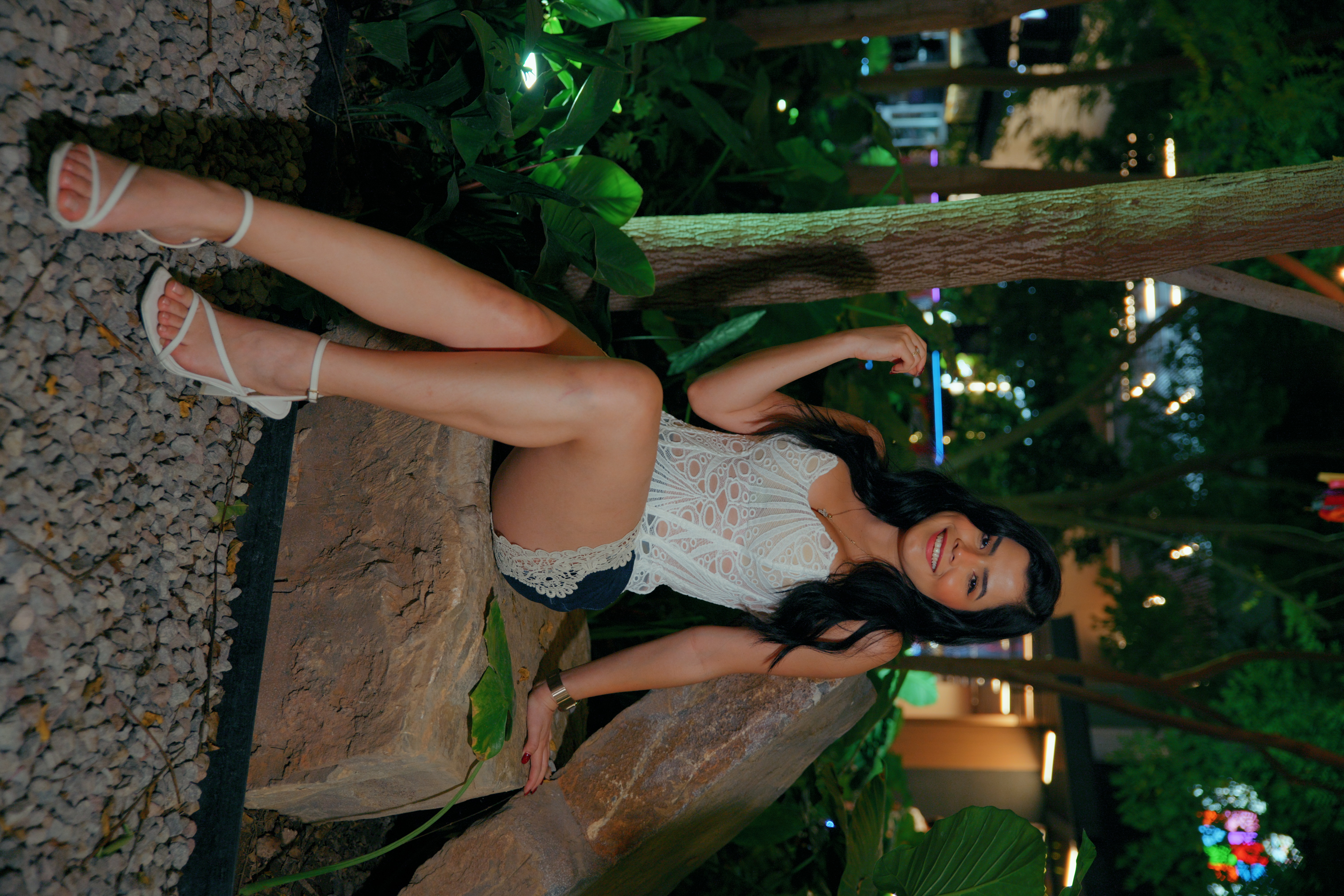 Retrato de una mujer en un jardín iluminado durante la noche