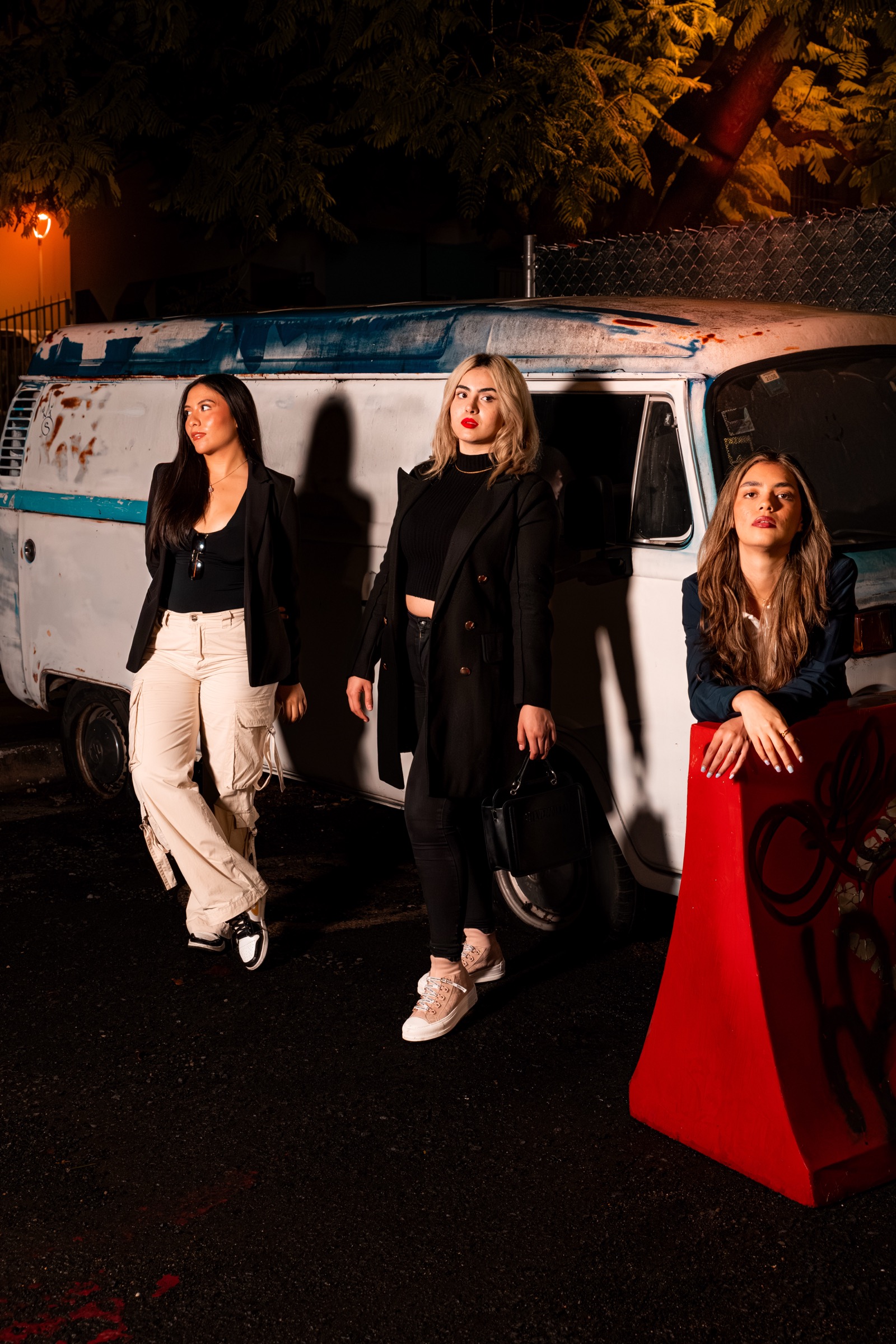 Retrato editorial de tres mujeres junto a una camioneta antigua