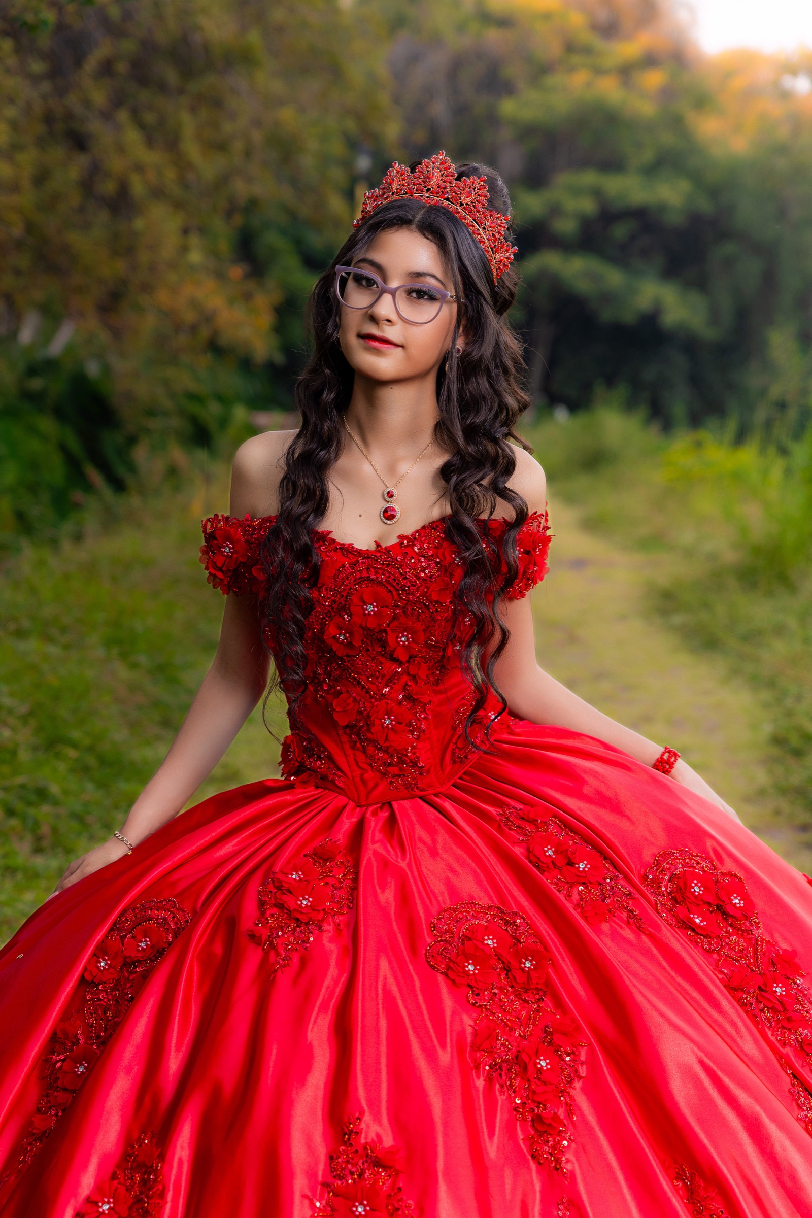 Retrato de una joven con vestido rojo y corona en exteriores