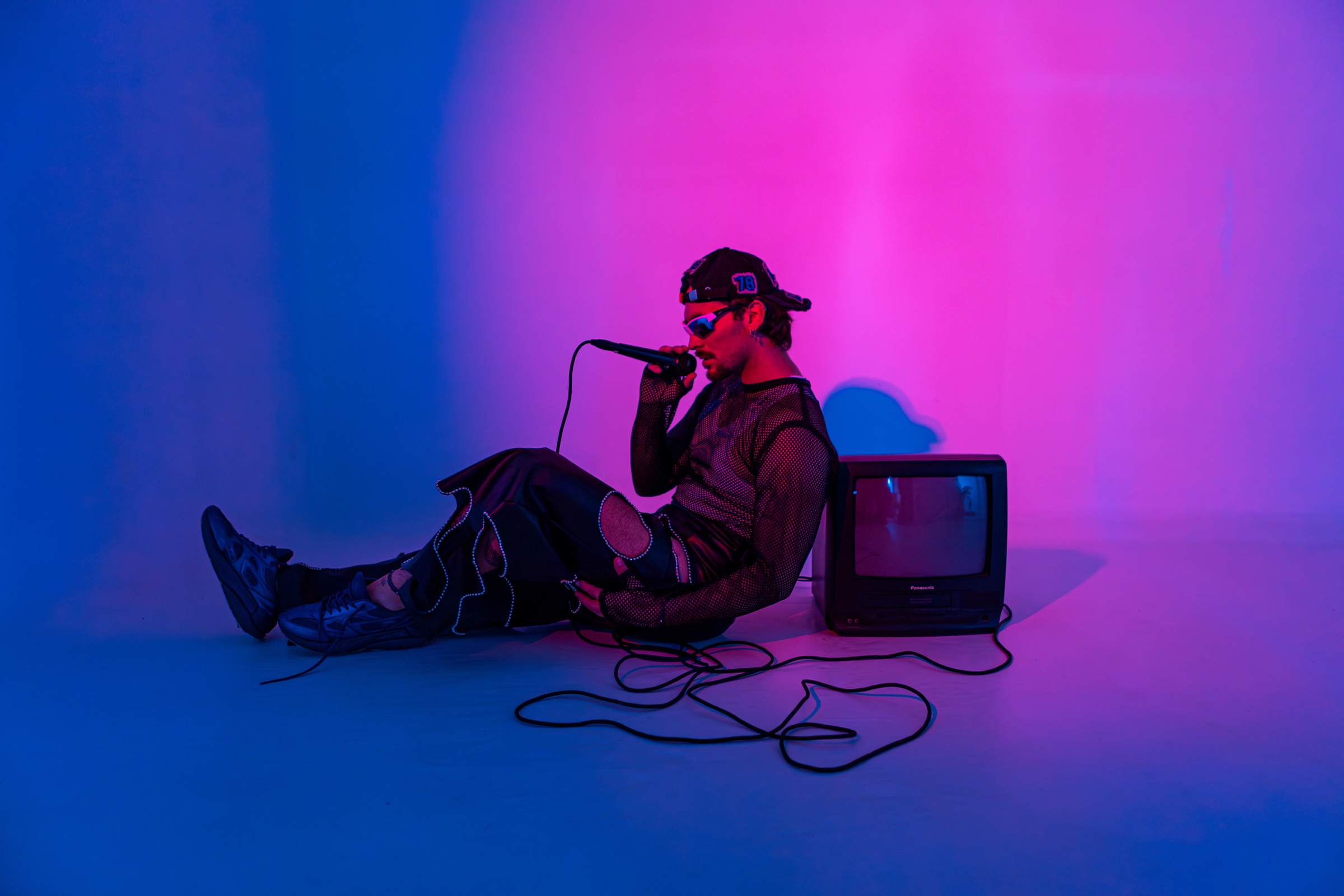 Retrato editorial de un cantante con iluminación azul y magenta